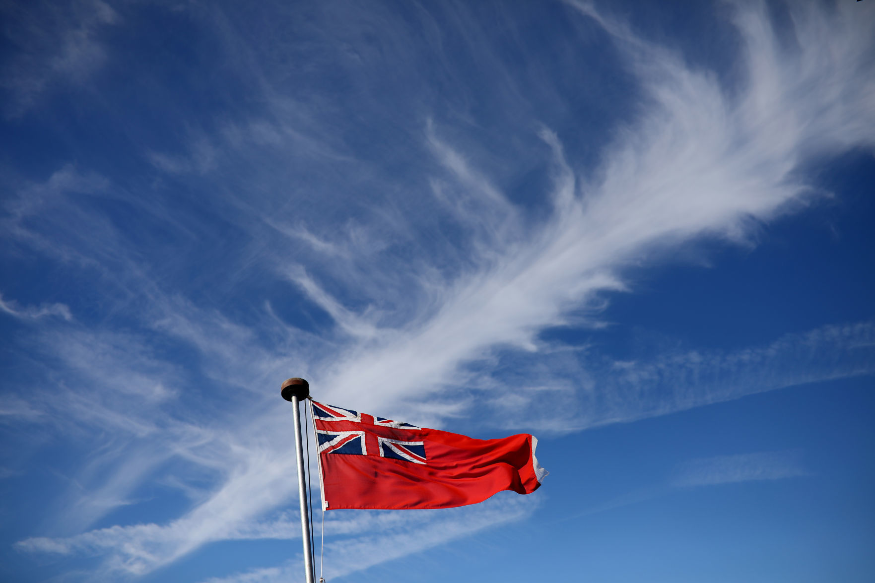 Cirrus clouds and some contrails are seen above a Red Ensign flag on the ferry MS Oldenburg during the Cloud Appreciation Society's gathering in Lundy